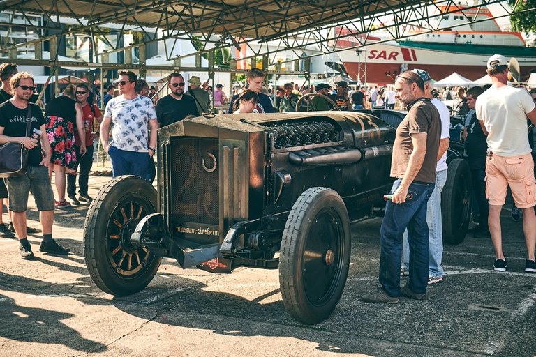 Ein historischer Rennwagen mit freiliegendem Flugmotor beim Brazzeltag im Technik Museum Speyer, umringt von Besuchern