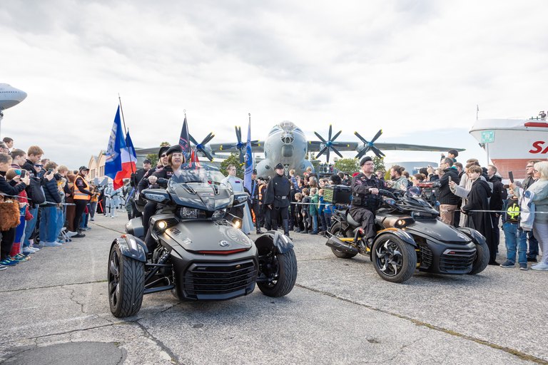 Eine Fahrzeugparade beim Science Fiction Treffen im Technik Museum Speyer: zwei dreirädrige Fahrzeuge rollen zwischen den Zuschauern, dahinter ein Propellerflugzeug