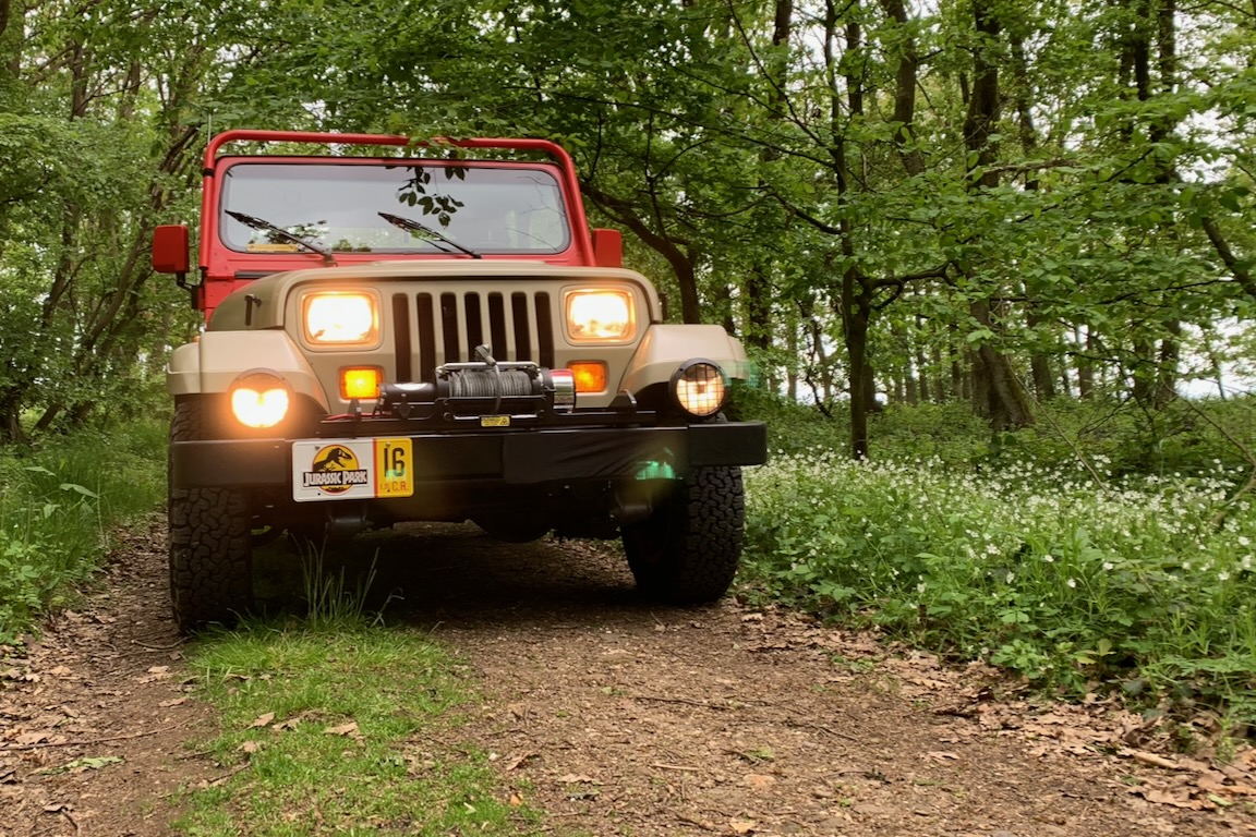 Jeep Wrangler Sahara in „Jurassic Park“-Optik mit Beleuchtung auf einem Waldweg