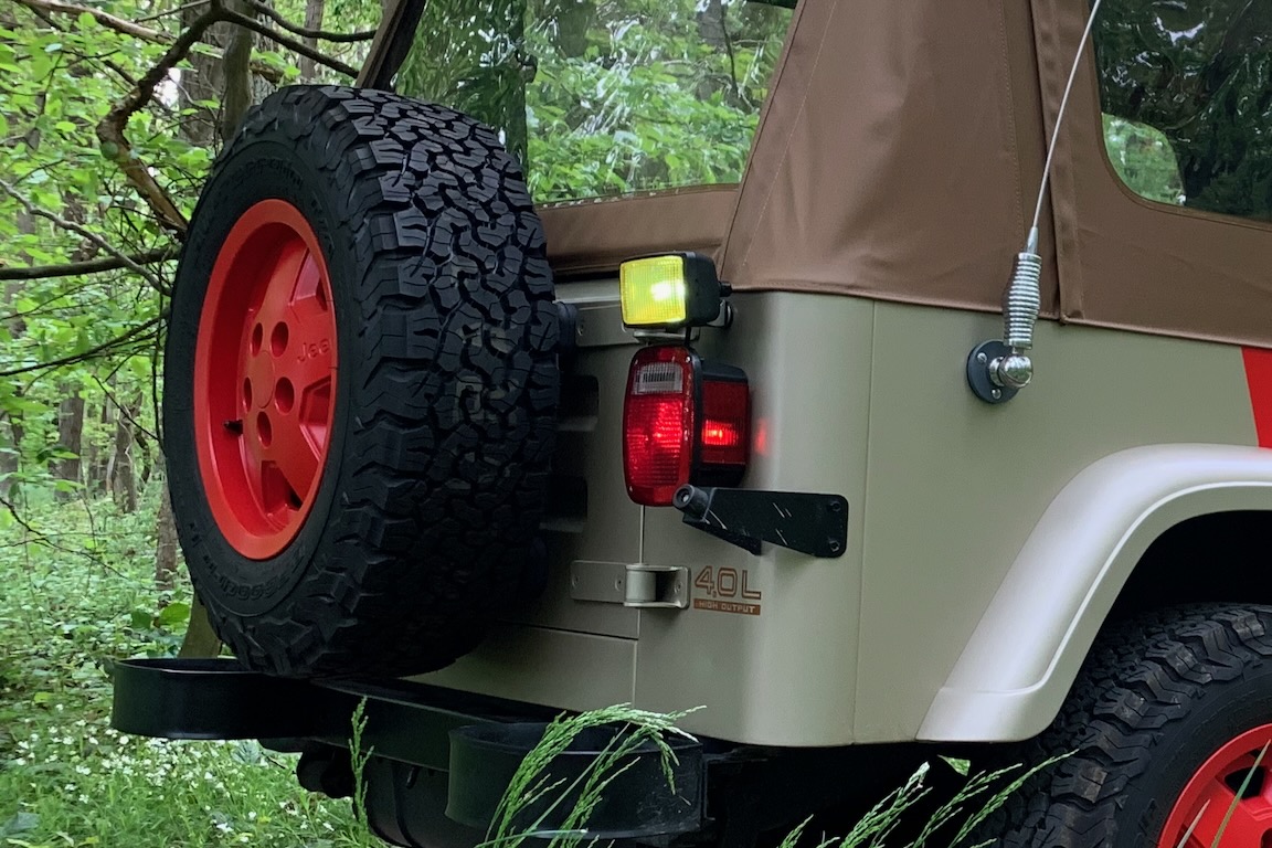 Eingeschaltete, rückwärts gerichtete Arbeitsscheinwerfer am Heck eines Jeep Wrangler Sahara in „Jurassic Park“-Optik