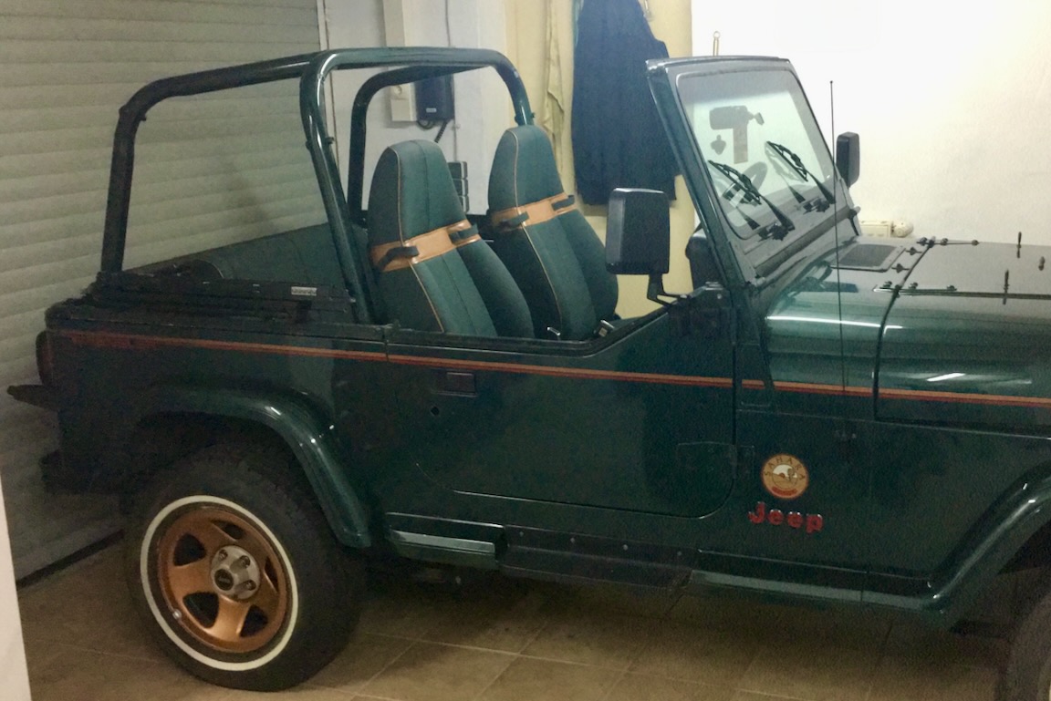 Jeep Wrangler Sahara in Hunter Green mit Badge auf dem vorderen Kotflügel und den Felgen der Modellvariante